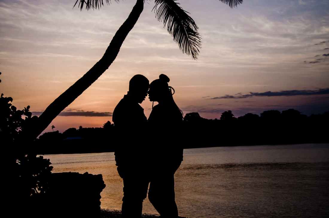 two person hugging near tree during sunset